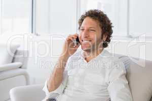Smiling man using mobile phone at home