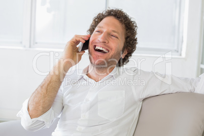 Cheerful man using mobile phone at home