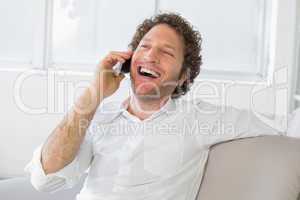 Cheerful man using mobile phone at home