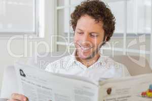 Smiling man reading newspaper at home