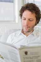 Young man reading newspaper at home