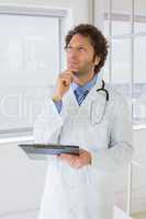 Thoughtful male doctor with reports in hospital