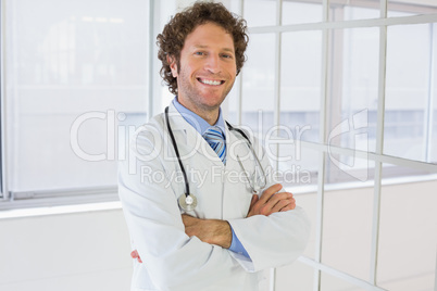 Male doctor standing with arms crossed in hospital