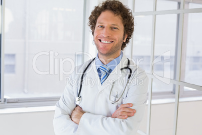 Happy male doctor with arms crossed in hospital