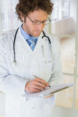 Serious male doctor writing reports in hospital