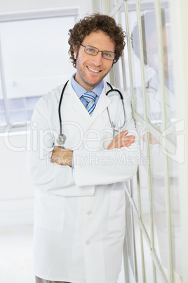 Handsome male doctor standing with arms crossed in hospital