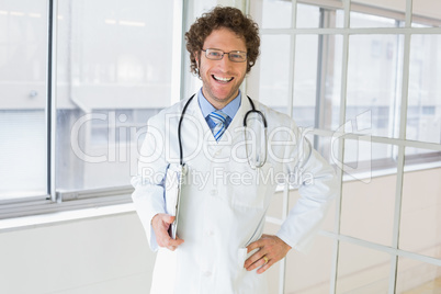 Happy handsome male doctor with clipboard in hospital