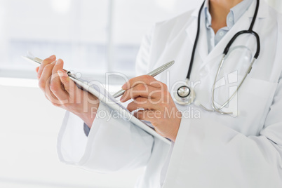 Mid section of a female doctor writing reports