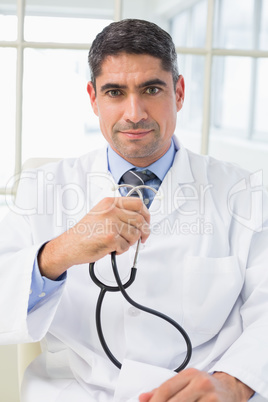 Serious male doctor holding stethoscope Serious male doctor holding stethoscope