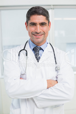 Smiling male doctor with arms crossed in hospital