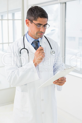 Male doctor reading reports in hospital