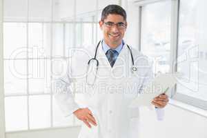 Smiling male doctor holding reports in hospital