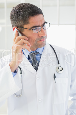 Serious male doctor using mobile phone