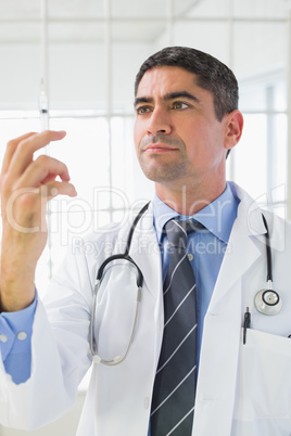 Serious male doctor holding an injection
