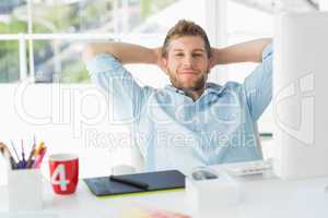 Designer relaxing at his desk smiling at camera