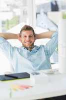 Handsome designer relaxing at his desk smiling at camera