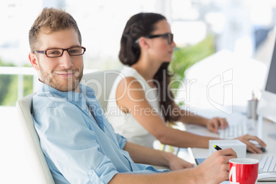 Handsome designer smiling at camera at desk Handsome designer smiling at camera at desk