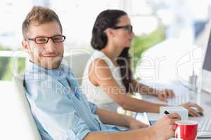 Handsome designer smiling at camera at desk