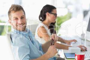 Attractive designer smiling at camera at desk