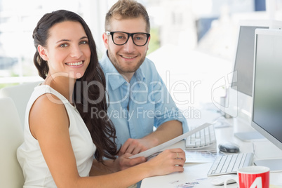 Team of designers smiling at camera together at desk