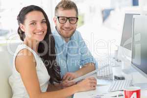 Team of designers smiling at camera together at desk