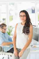 Beautiful designer smiling at camera leaning on desk