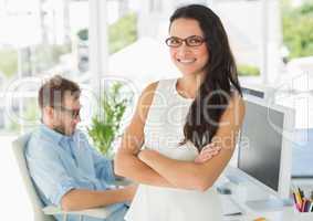 Pretty designer smiling at camera leaning on desk