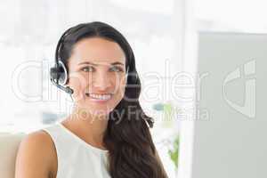 Happy call centre agent sitting at her desk