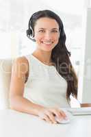 Smiling call centre agent sitting at her desk
