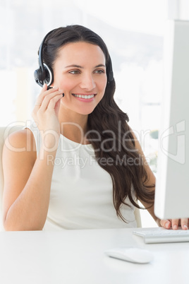 Pretty call centre agent sitting at her desk on a call