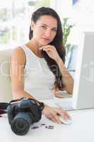 Focused photographer sitting at her desk using computer looking