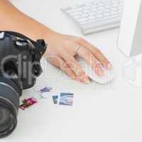 Digital camera on photographers desk with womans hand on mouse
