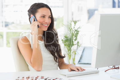 Beautiful photographer talking on phone at her desk