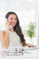Beautiful editor on telephone at her desk smiling at camera