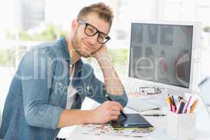 Handsome editor working with graphics tablet smiling at camera