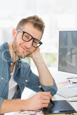 Handsome designer working with graphics tablet smiling at camera