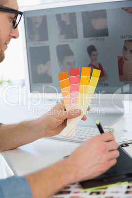 Handsome designer working with digitizer holding colour chart at