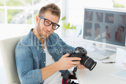 Handsome photographer holding his camera smiling at camera