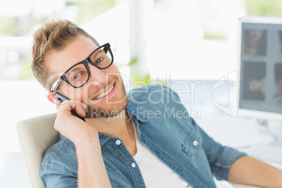 Editor talking on the phone at his desk smiling at camera