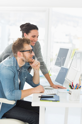 Team of smiling designers looking at the computer