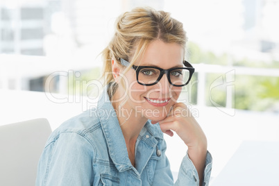 Blonde designer wearing glasses smiling at camera