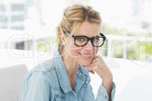 Blonde designer wearing glasses smiling at camera