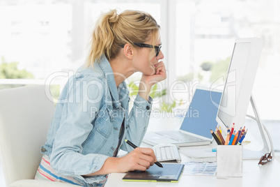 Blonde pretty designer using digitizer at her desk