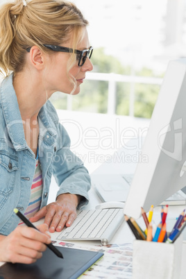 Blonde focused designer using digitizer at her desk