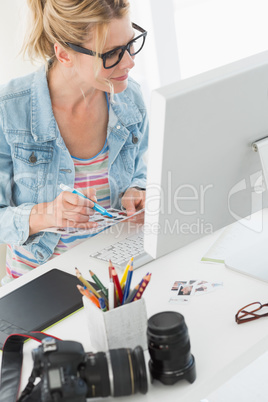 Blonde photographer looking over contact sheet at desk