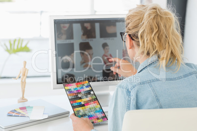 Blonde designer using a colour chart at her desk
