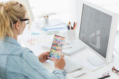Blonde designer holding colour swatch at her desk
