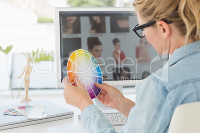 Blonde focused designer working at her desk holding a colour whe