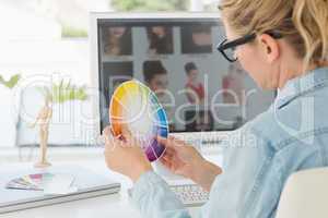 Blonde focused designer working at her desk holding a colour whe