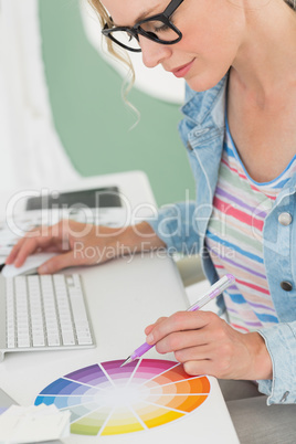 Smiling designer working at her desk using a colour wheel